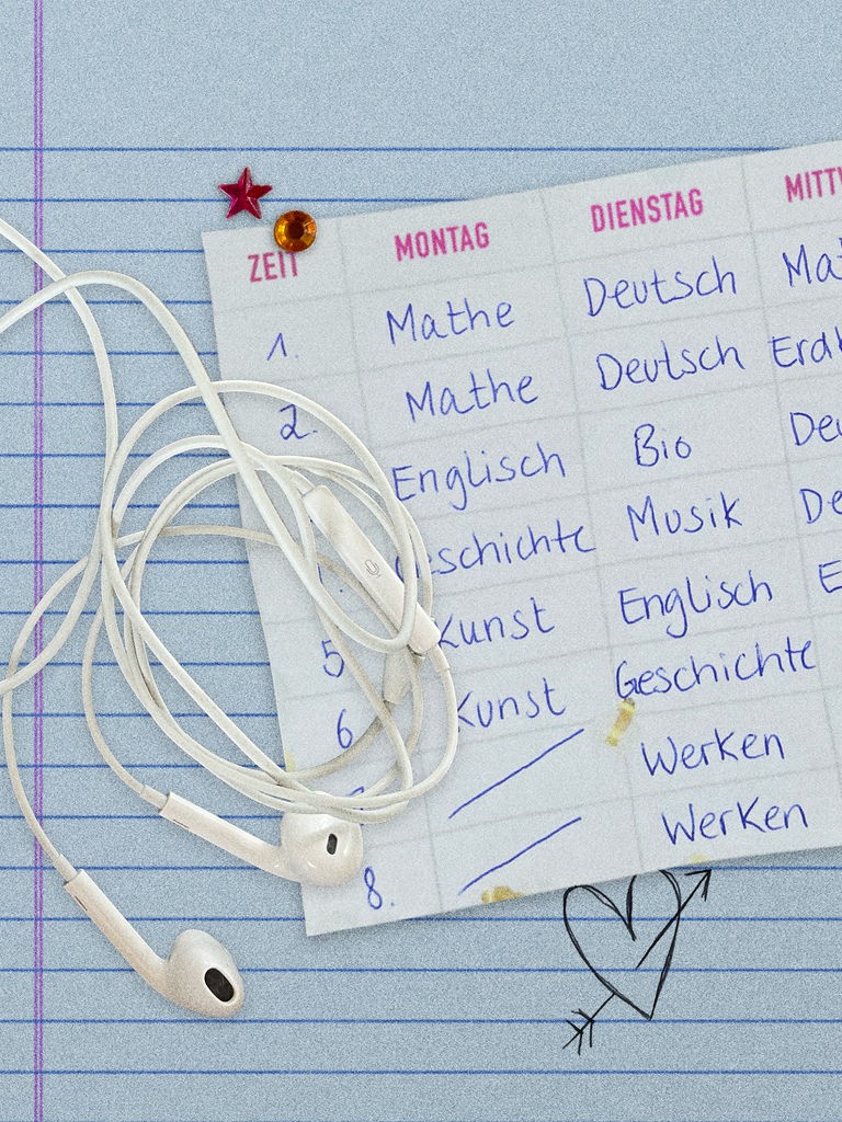 Ein Stundenplan und Kopfhörer liegen auf einem linierten Blatt, darunter ist ein gezeichnetes Herz