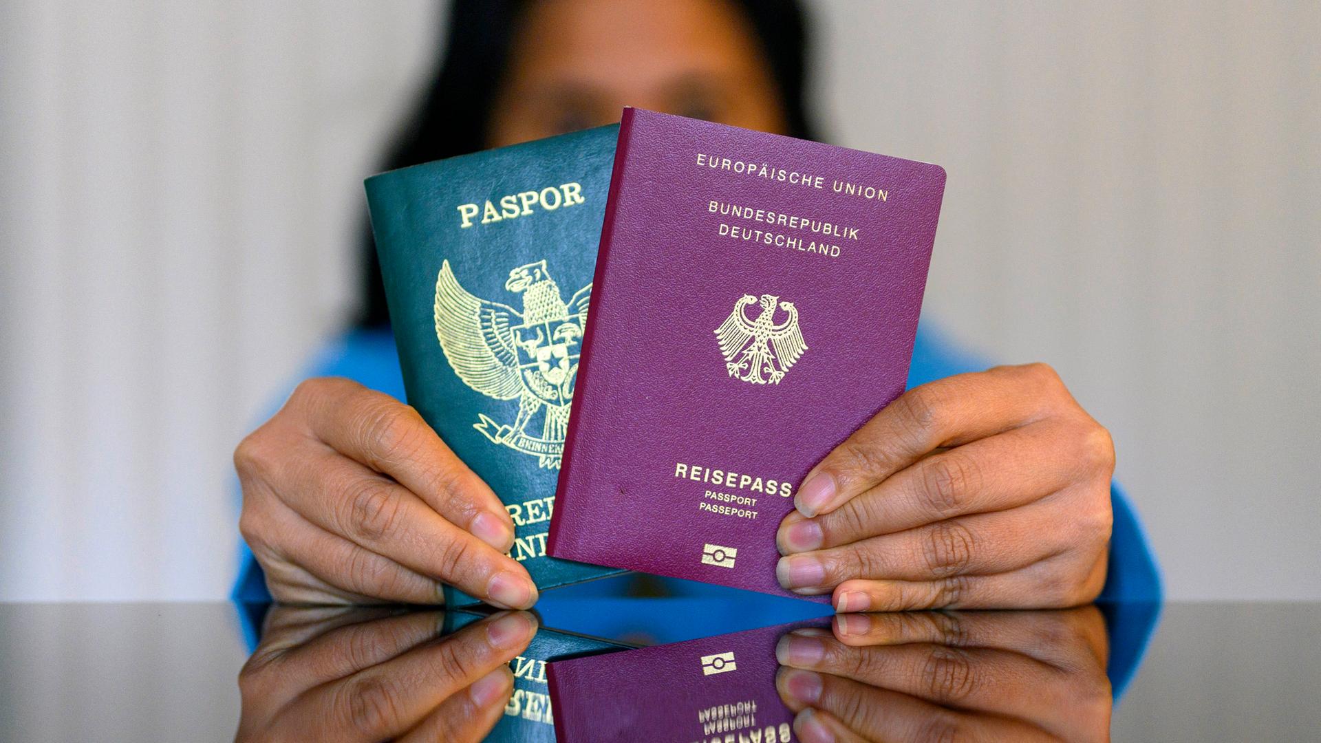 Eine Frau hält einen indonesischen und einen deutschen Pass in den Händen. 