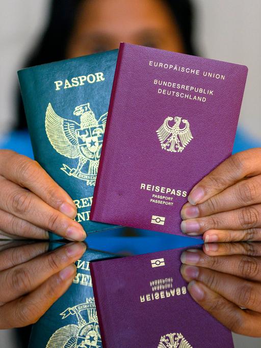 Eine Frau hält einen indonesischen und einen deutschen Pass in den Händen. 