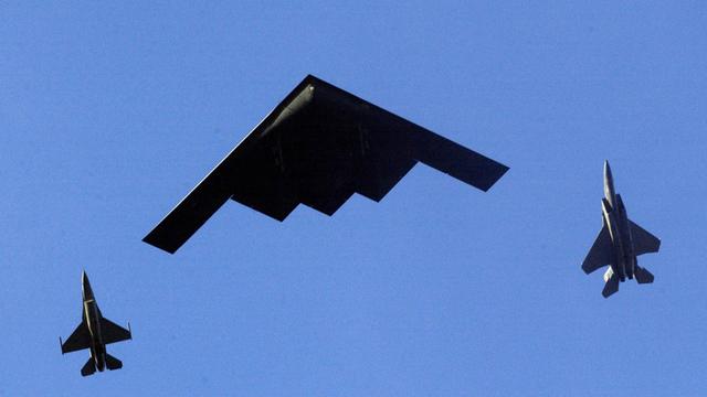 Ein Tarnkappenbomber fliegt in der Luft. Neben ihm sind zwei Kampfjets. 
