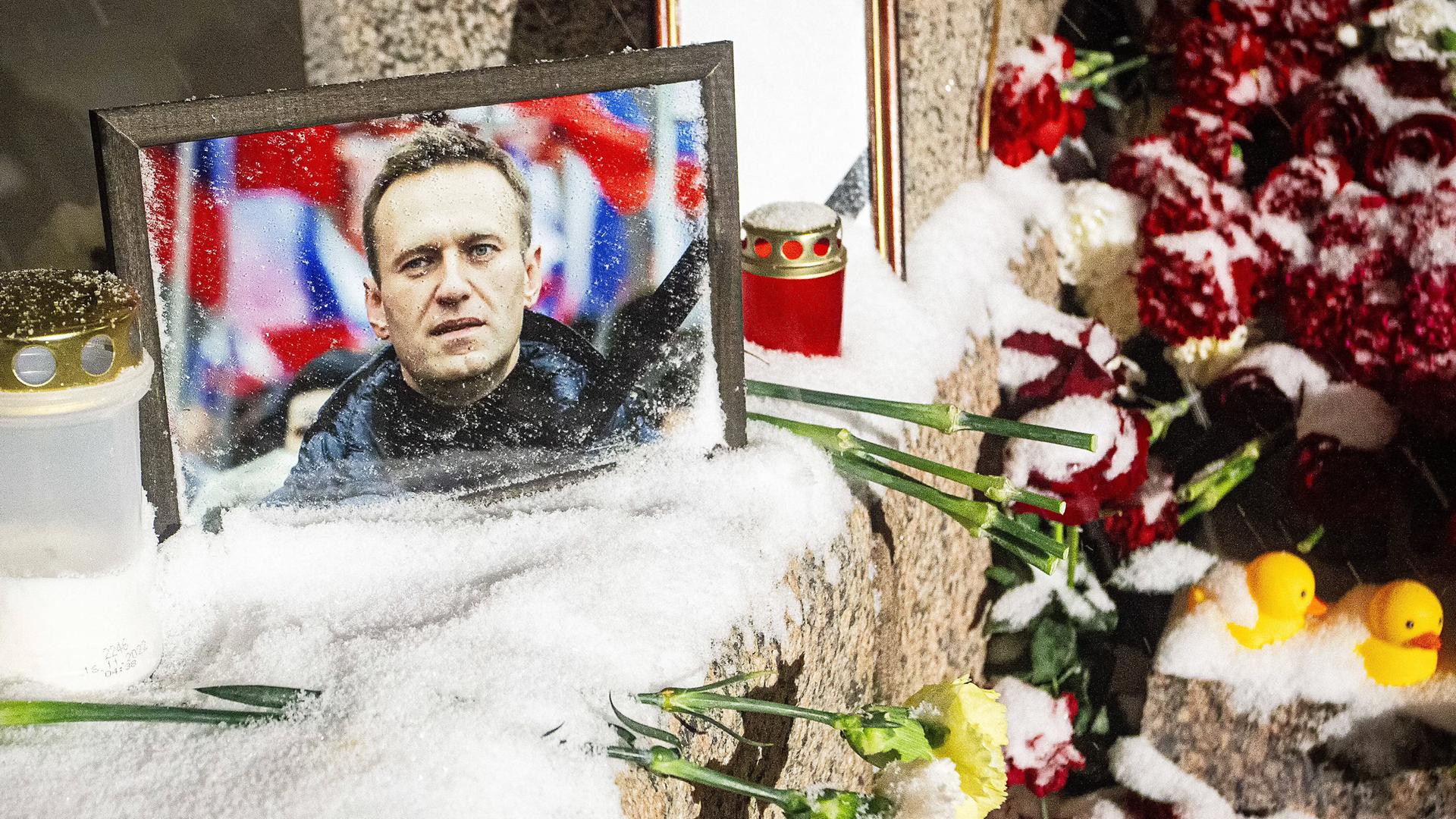 Ein Bild von Alexej Nawalny steht in Sankt Petersburg auf einmal Denkmal für die Opfer politischer Repression. Daneben haben Menschen Blumen niedergelegt.