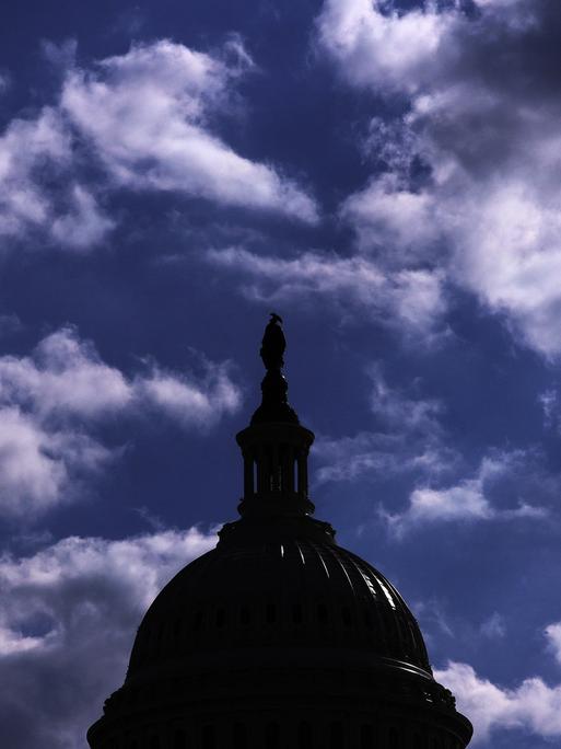 Das Dach des Kapitols in Washington hebt sich dunkel vor einem bewölkten Himmel ab.