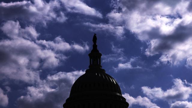 Das Dach des Kapitols in Washington hebt sich dunkel vor einem bewölkten Himmel ab.