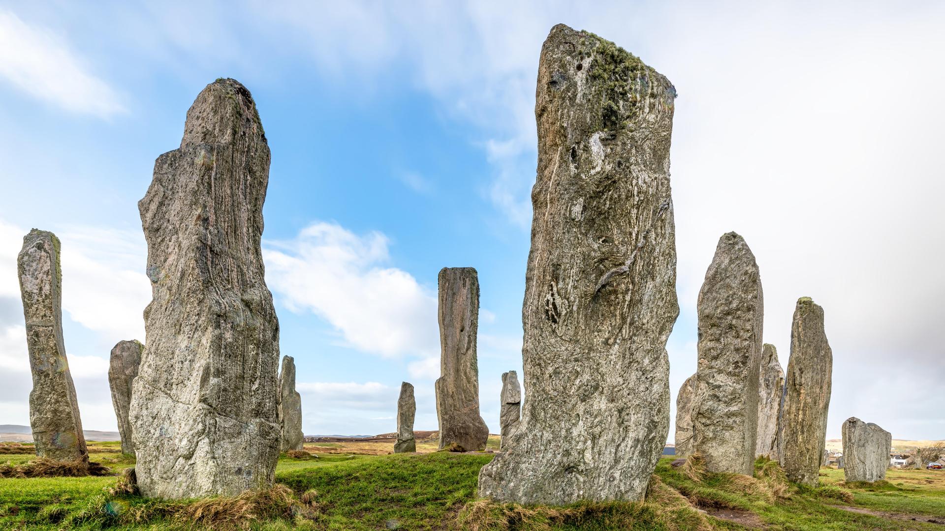 Monolithen stehen in einer Graslandschaft vor wolkigem Himmel Monolithen stehen in einer Graslandschaft vor wolkigem Himmel