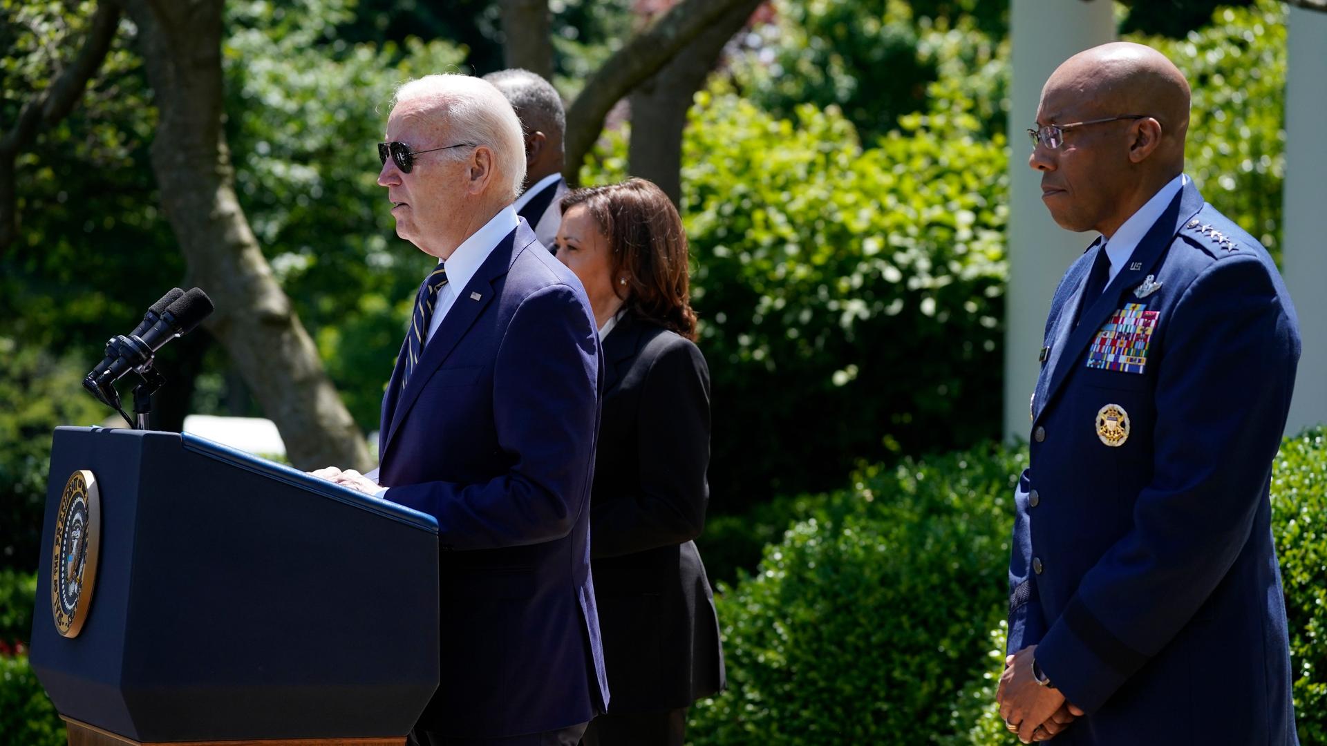 Joe Biden steht an einem Redepult im Freien, rechts versetzt hinter ihm steht Charles Brown. Im Hintergrund ist grüne Flora zu erkennen.