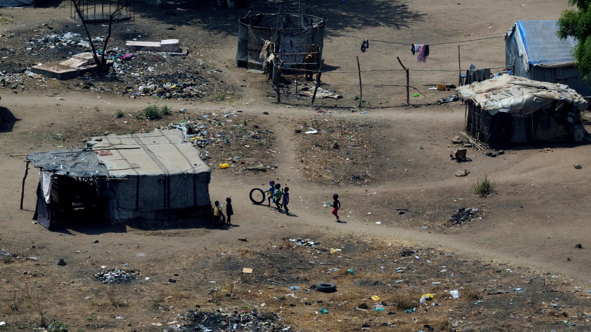 Kinder spielen in den Straßen der Stadt Juba im Südsudan. Es liegt viel Müll auf den Wegen und man sieht zerfallene Hütten.