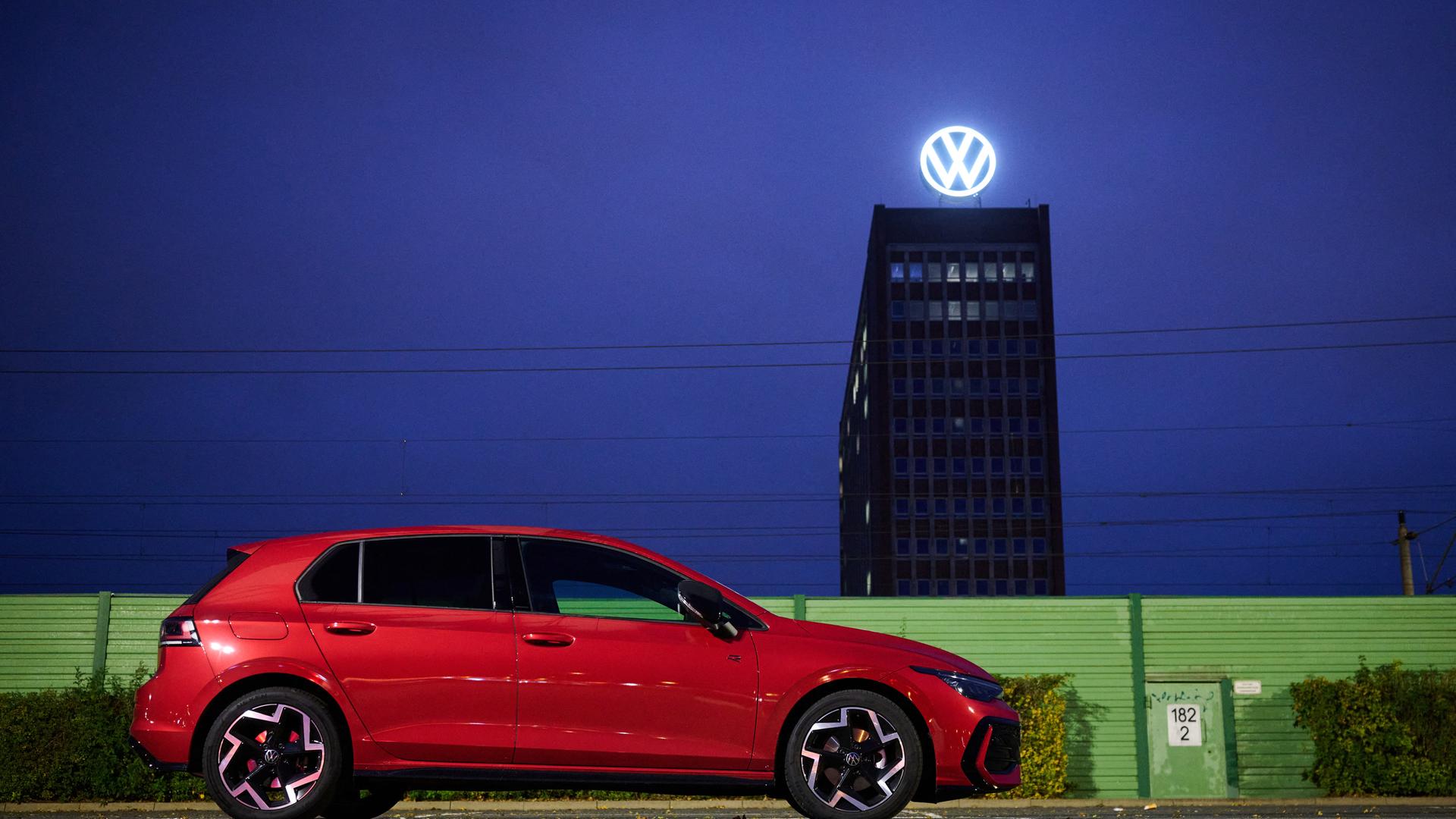 Ein roter VW Golf steht auf einem Parkplatz vor dem VW-Werk.