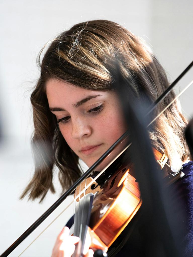 Eine Jugendliche mit schulterlangen braunen Haaren spielt konzentriert Geige.