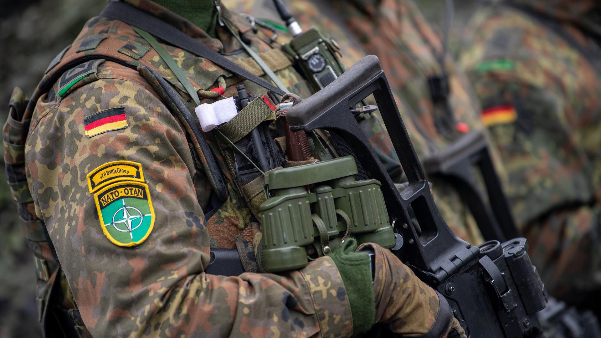 Soldaten der deutschen Bundeswehr und NATO Emblem an der Kleidung, in voller Ausrüstung.