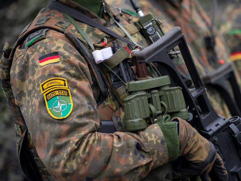 Soldaten der deutschen Bundeswehr und NATO Emblem an der Kleidung, in voller Ausrüstung.