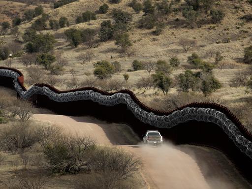 Eine Fahrzeug der Grenzsicherung fährt entlang der Mauer in Arizona
