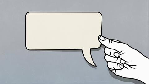 Eine Hand hält eine Sprechblase fest.