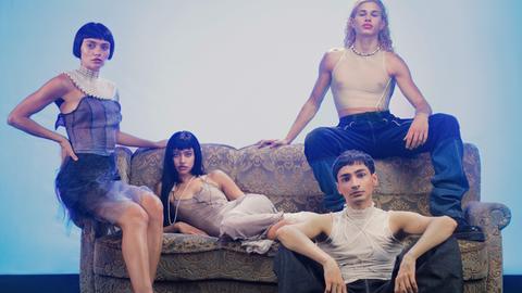 Studiofoto mit den ukrainischen und russischen Models Valeriia Karamann (links), Tanya Chudnovskaia (2. von links) Daniel Nikiforow (rechts oben) und Regisseur und Fotograf Mehran Djojan (rechts unten sitzend). Die jungen Leute sind stylisch frisiert und gekleidet.