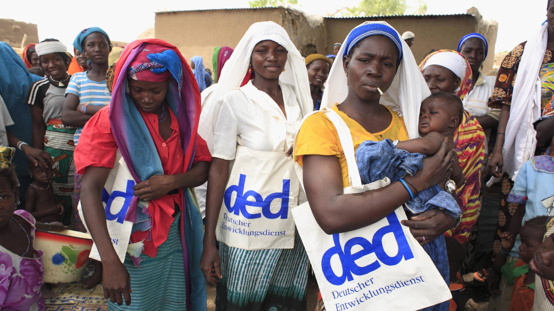 Frauen in einem Dorf der Region FadaNgourma in Burkina Faso tragen Taschen mit dem Logo des DED (Deutscher Entwicklungsdienst).