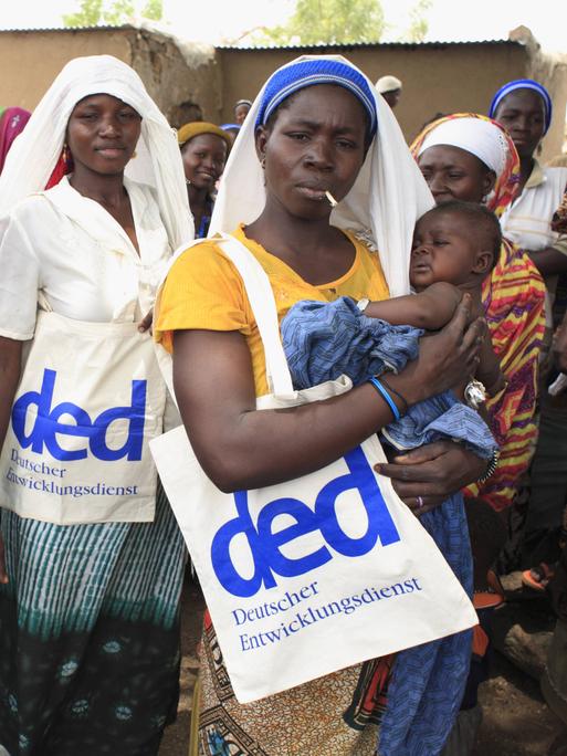 Frauen in einem Dorf der Region FadaNgourma in Burkina Faso tragen Taschen mit dem Logo des DED (Deutscher Entwicklungsdienst).