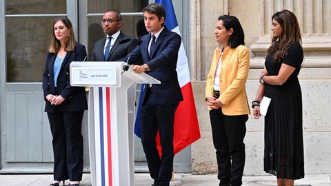 Der neu ernannte französische Bildungsminister Gabriel Attal hält eine Rede. Er steht an einem Pult, das mit einer Trikolore geschmückt ist.