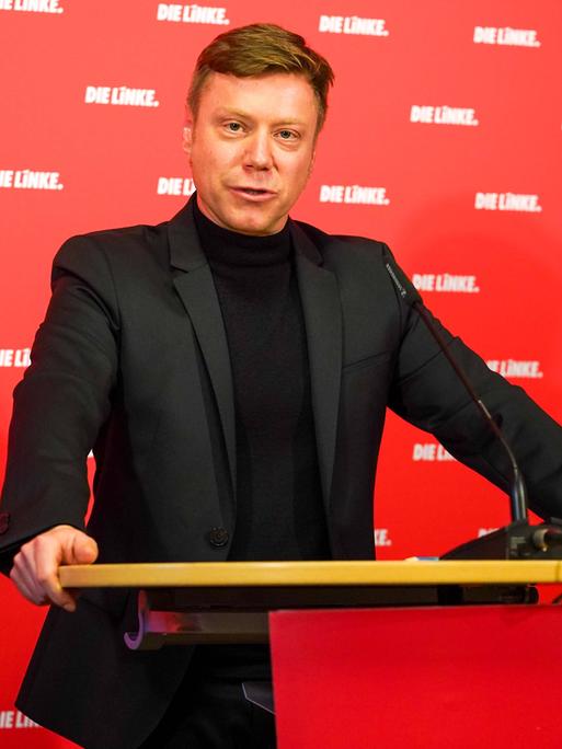 Martin Schirdewan, Co-Vorsitzender der Linken, steht vor einer roten Tapete mit weißem "Linke" Aufdruck hinter einem Rednerpult.