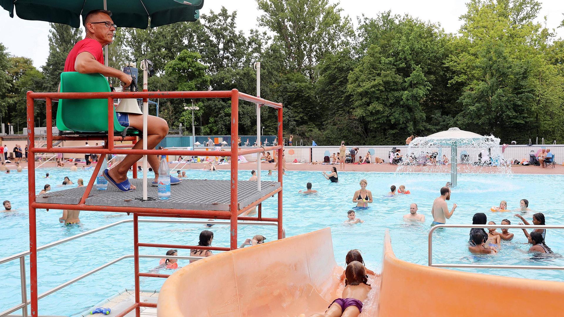Freibad, orangefarbene Rutsche, Bademeister, Wasserpilz. Sommerbad Kreuzberg, Prinzenbad in Berlin.