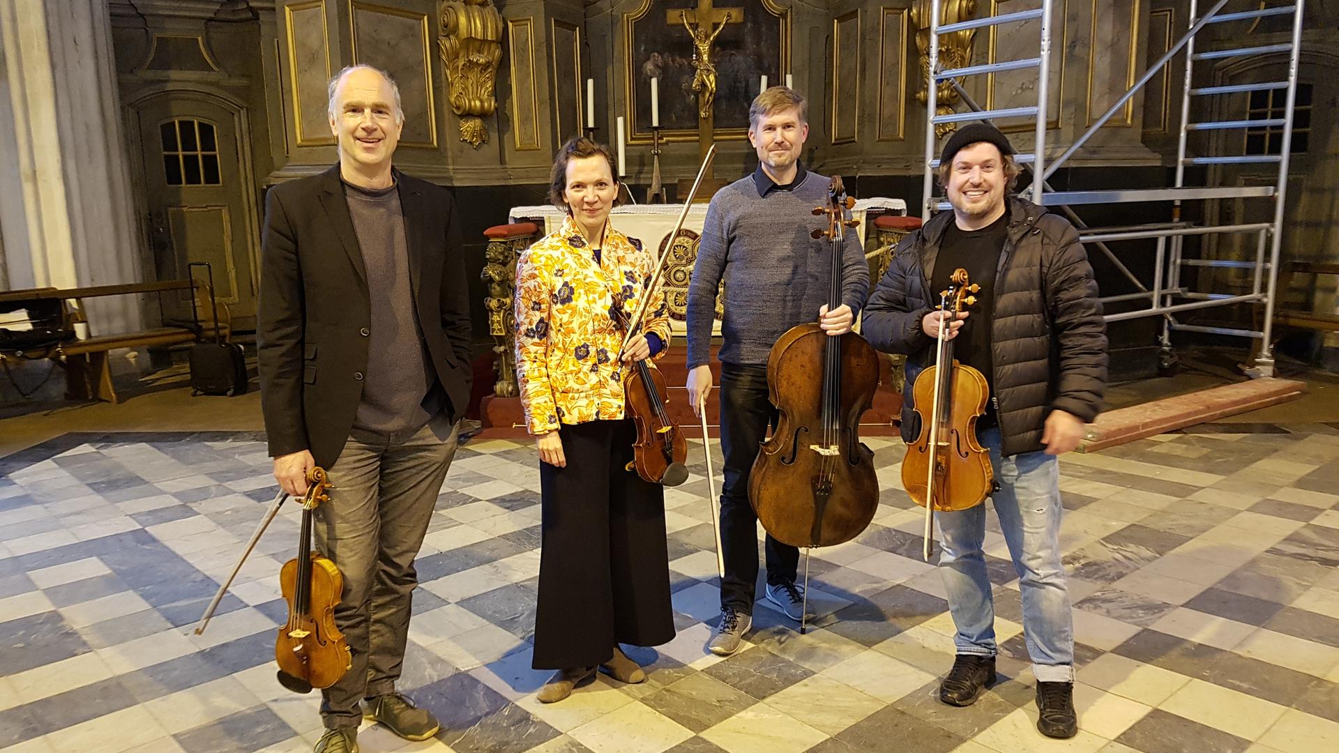 Drei Musiker und eine Musikerin stehen mit ihren Instrumenten (Violinen und ein Kontrabass) in der Rostocker Marienkirche Drei Musiker und eine Musikerin stehen mit ihren Instrumenten (Violinen und ein Kontrabass) in der Rostocker Marienkirche