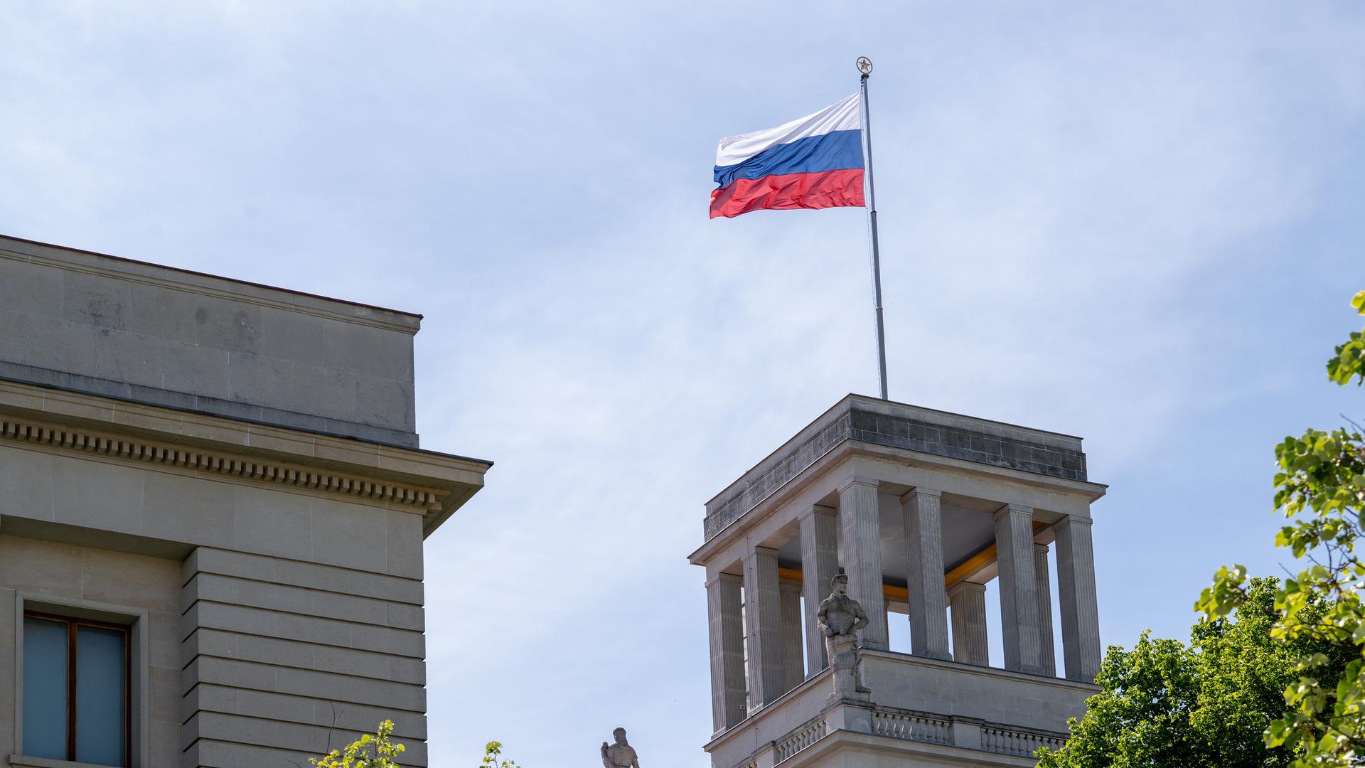 Das Bild zeigt einen Teil des russischen Botschaftsgebäudes in Berlin. Auf einem quadratförmigen Betonturm weht die russische Flagge. 