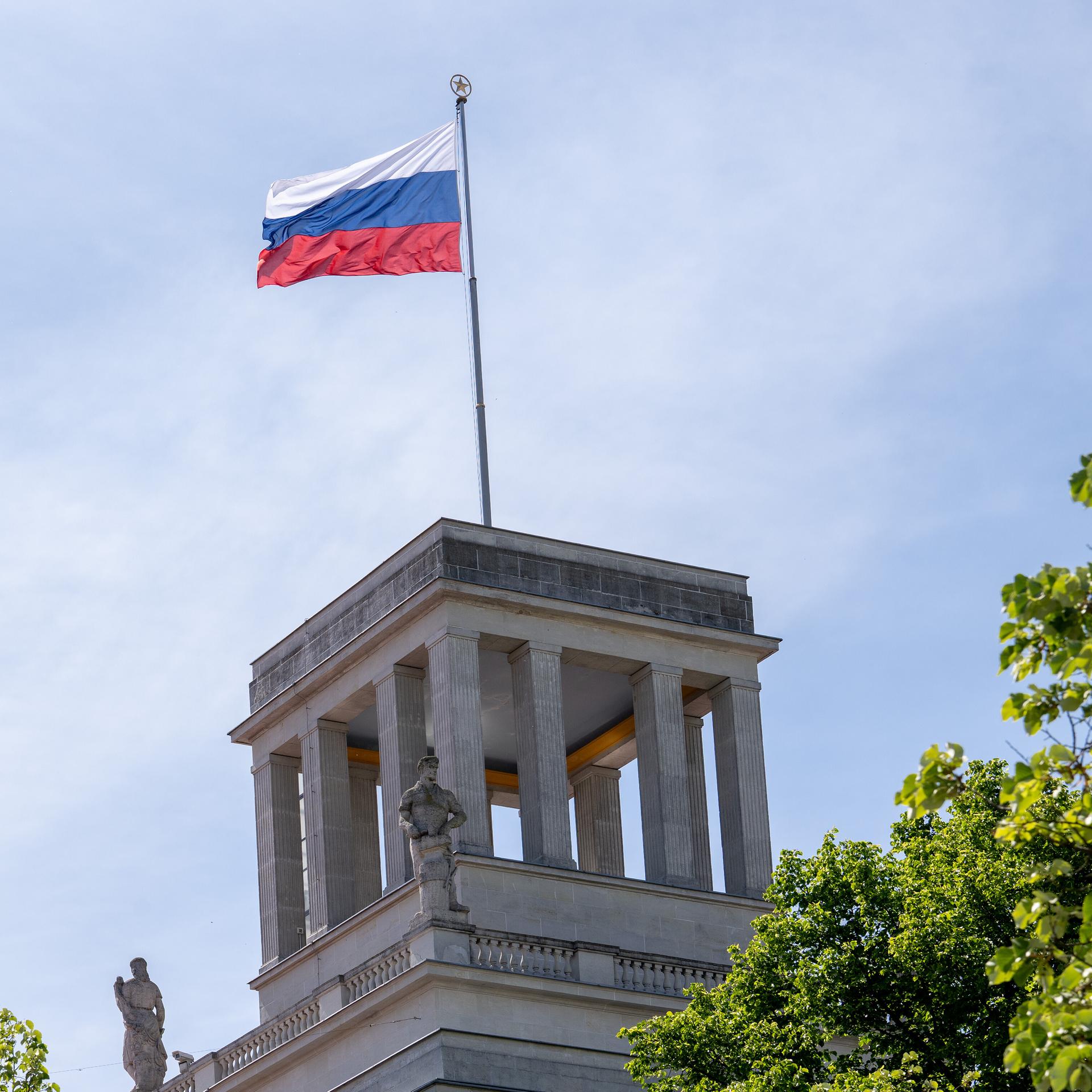 Das Bild zeigt einen Teil des russischen Botschaftsgebäudes in Berlin. Auf einem quadratförmigen Betonturm weht die russische Flagge. 