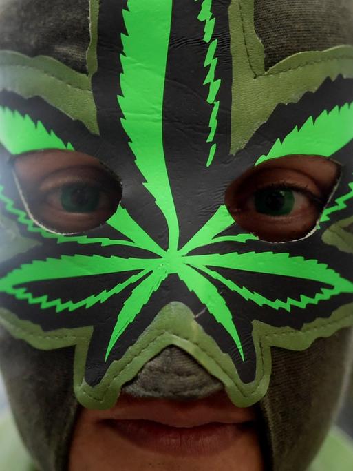Ein Mann trägt eine Maske mit der Darstellung eines Cannabisblattes.