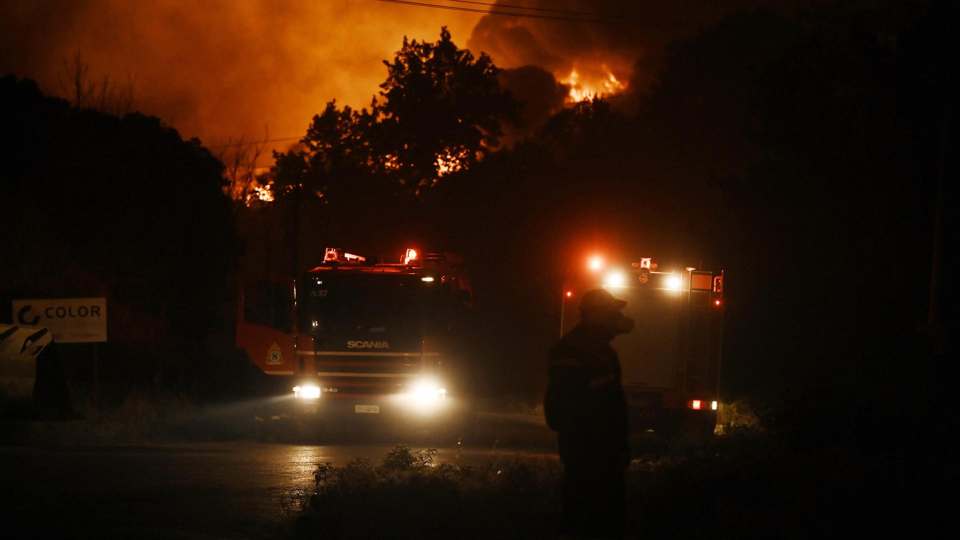 Flammen erleuchten den Nachthimmel über Oreokastro, einem Vorort von Thessaloniki in Griechenland. Mittendrin steht ein Löschfahrzeug der Feuerwehr. Flammen erleuchten den Nachthimmel über Oreokastro, einem Vorort von Thessaloniki in Griechenland. Mittendrin steht ein Löschfahrzeug der Feuerwehr.