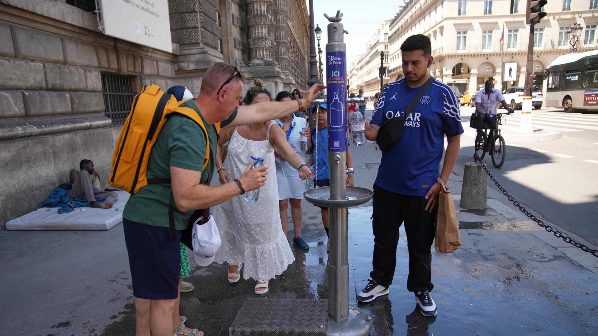 Während einer Hitzewelle nutzen Menschen einen Straßenbrunnen zur Abkühlung in Paris, Frankreich. 