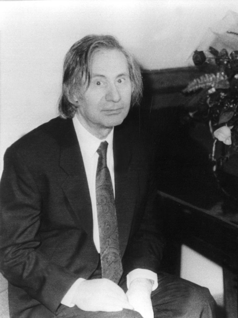 Auf dem Bild sieht man den Komponisten Alfred Schnittke vor einem Klavier sitzen. 