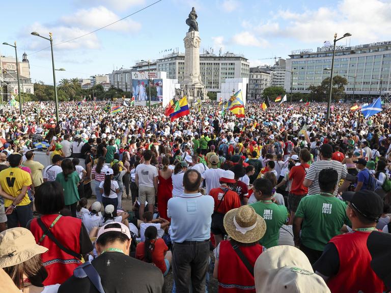 Das Foto zeigt viele Menschen auf einem Platz in der Stadt Lissabon. 