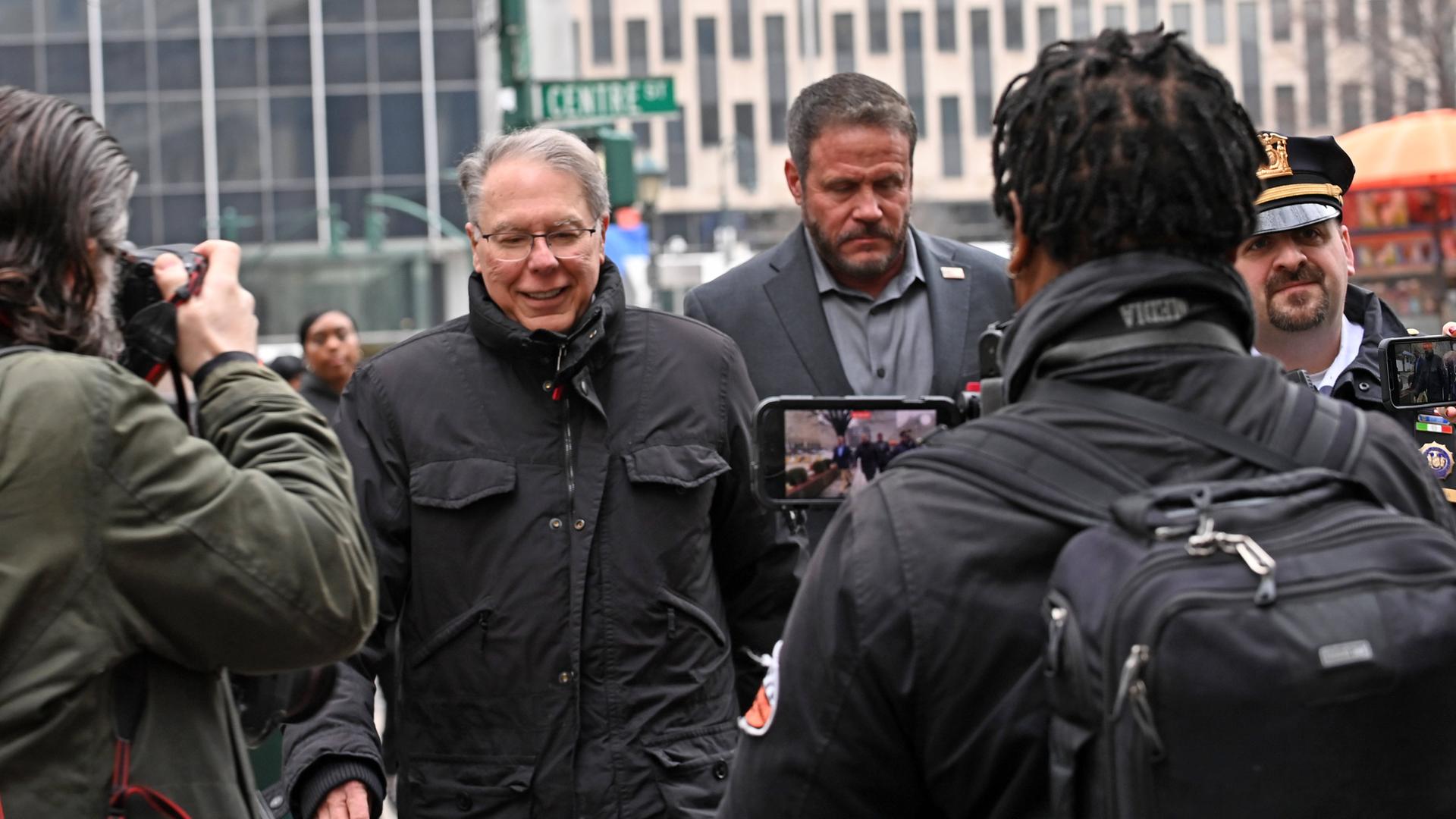 Der ehemalige NRA-Vorsitzende LaPierre geht umringt von Medienvertretern und Polizisten über eine Straße in Manhattan.