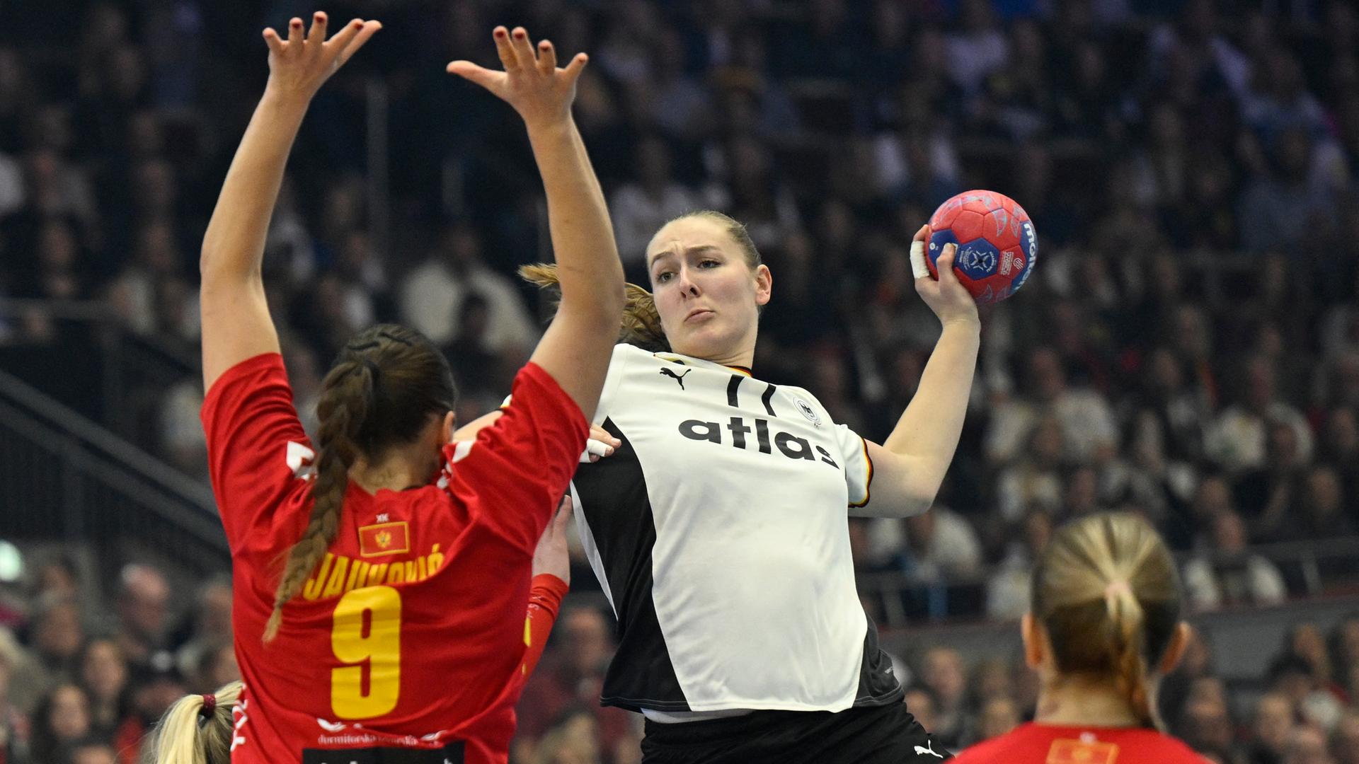 Leuchter holt zum Wurf aus. Eine gegnerische Spielerin reckt die Hände nach oben, um den Wurf zu blocken.