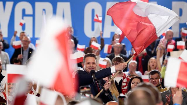 Rafał Trzaskowski schwenkt die polnische Flagge. Die Szene spielt sich am Sonntagabend, dem 18. Mai 2025, in Sandomierz ab. Im Hintergrund jubeln Unterstützer, viele halten kleine und große Polenfahnen in die Höhe. 