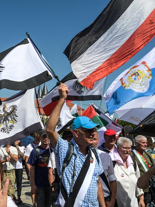 Sogenannte Reichsbürger marschieren mit Reichsfahnen auf dem Domplatz in Magdeburg. Zur Demonstration der "Reichsbürger"-Szene waren Teilnehmer aus der gesamten Bundesrepublik nach Magdeburg gereist.