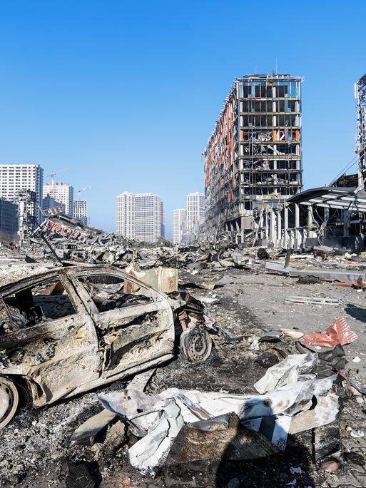 Die ukrainische Stadt Kiew nach einem russischen Luftschlag. Die Straßenflucht ist völlig zerstört, im Vordergrund ein ausgebranntes Auto. 