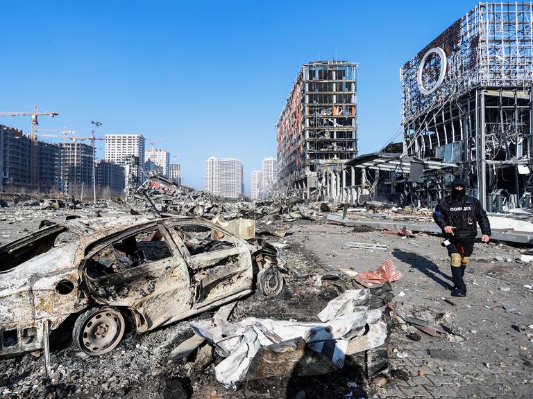 Die ukrainische Stadt Kiew nach einem russischen Luftschlag. Die Straßenflucht ist völlig zerstört, im Vordergrund ein ausgebranntes Auto. 