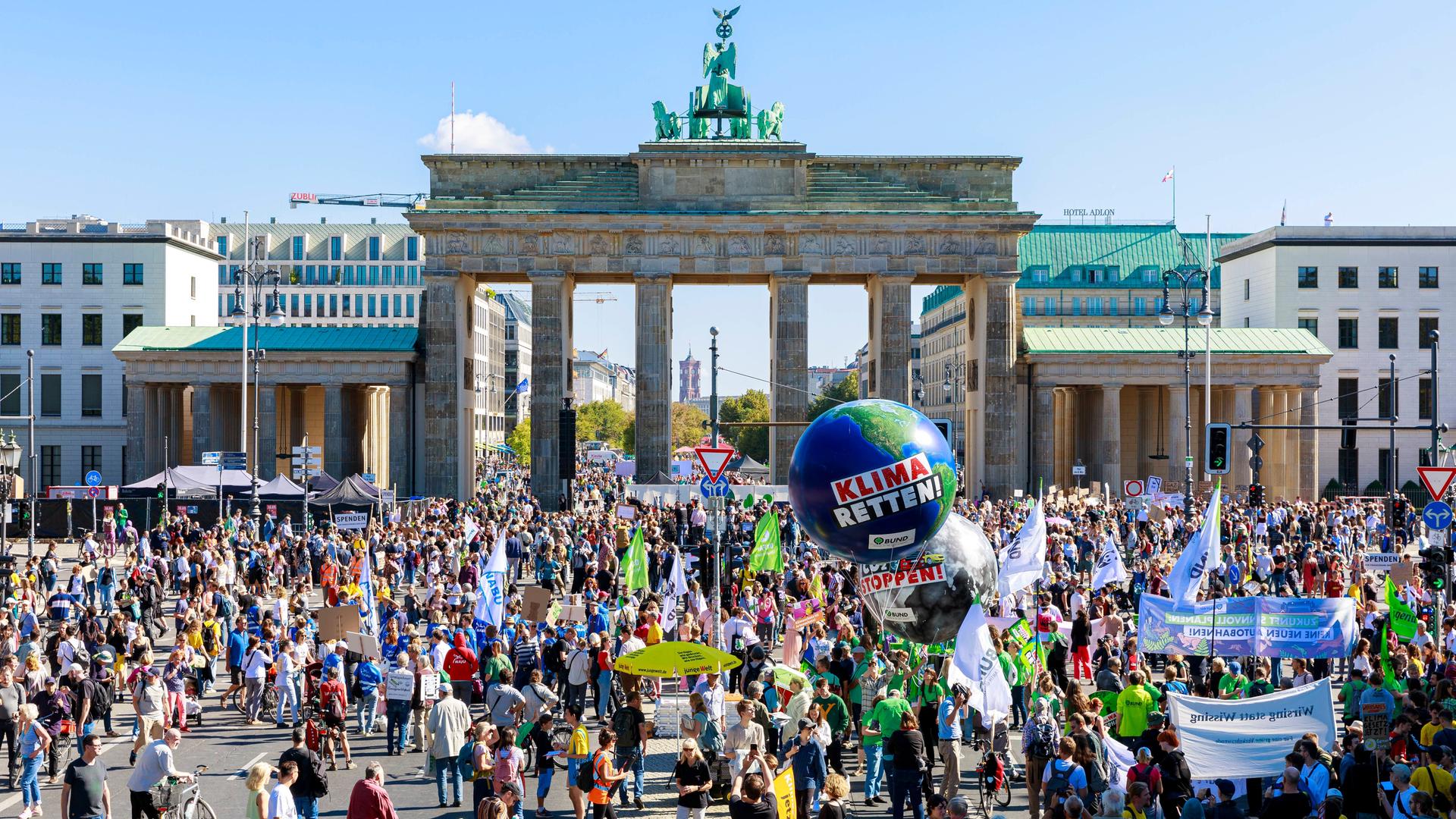 Klimademonstration in Berlin vor dem Brandenburger Tor. Über den Demonstranten schwebt ein großer Ballon mit der Aufschrift "Klima Retten".