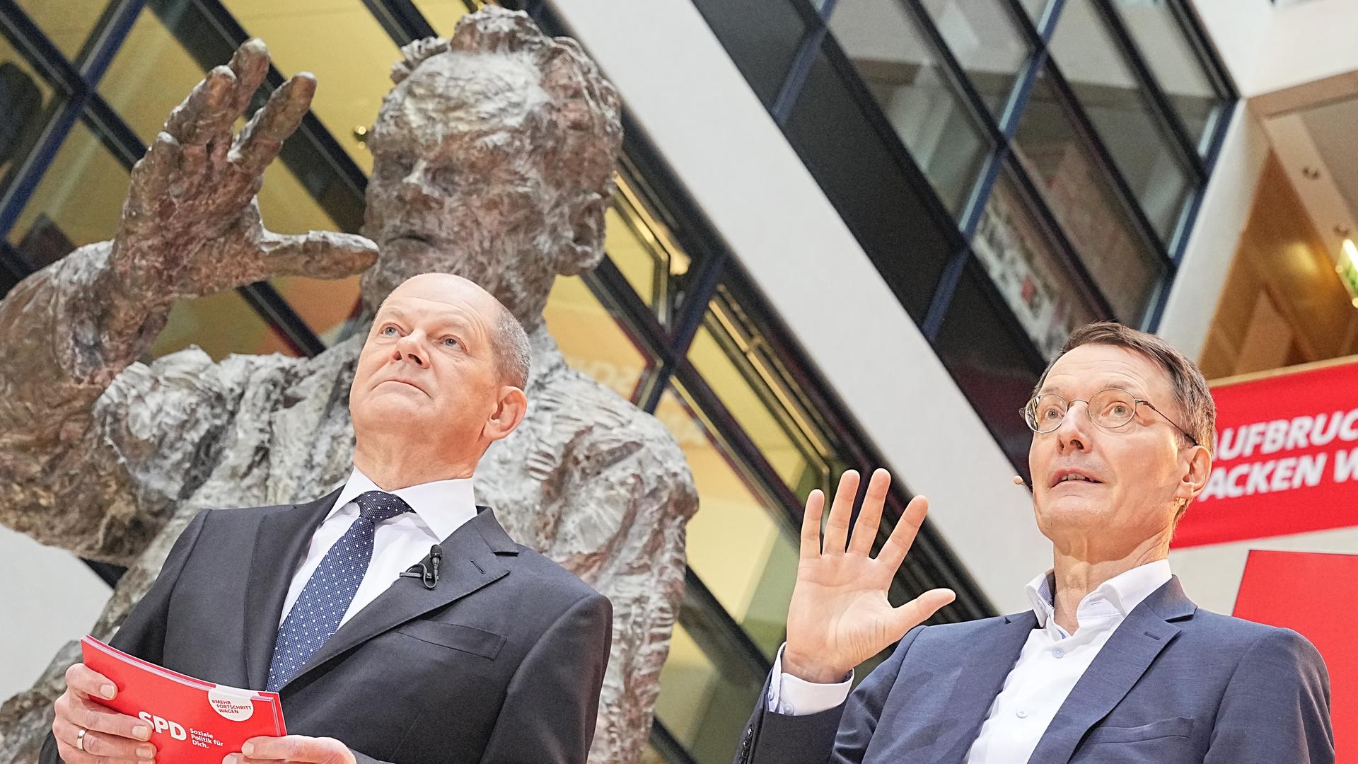 Die SPD-Politiker Olaf Scholz und Karl Lauterbach bei der Präsentation der sozialdemokratischen Ministerposten vor einer Statue von Willy Brandt. 