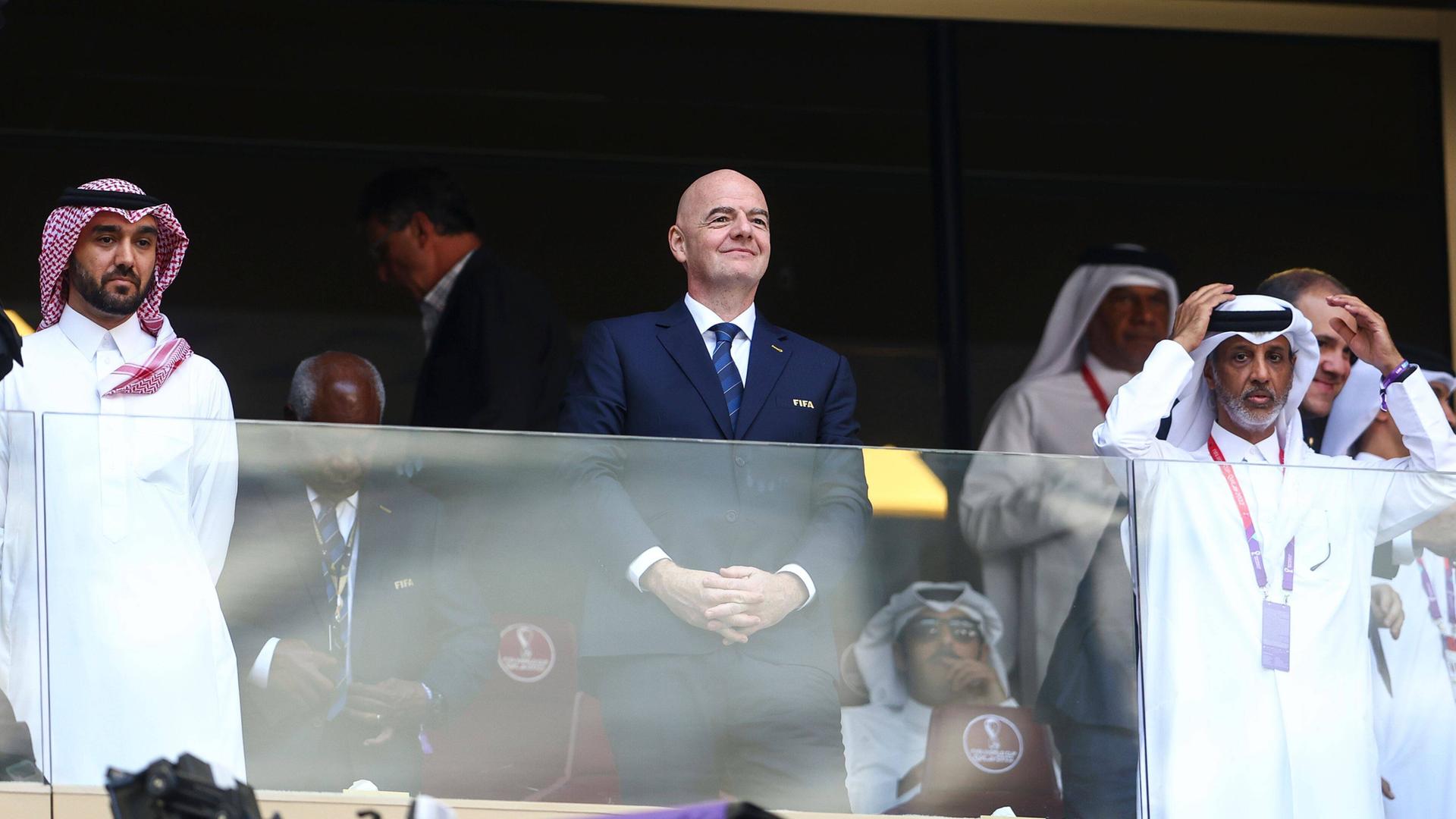 FIFA-Präsident Gianni Infantino bei dem WM in Katar auf der Tribüne. Neben ihm stehen saudische Offizielle. 