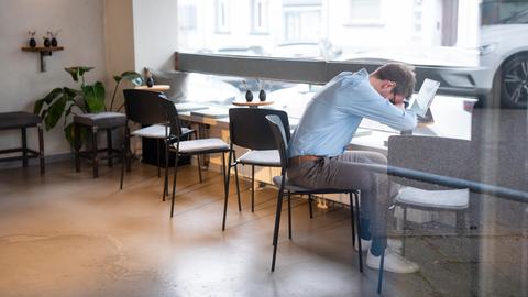 Geschäftsmann, der über seinem Tablet in einem Café ein Nickerchen macht