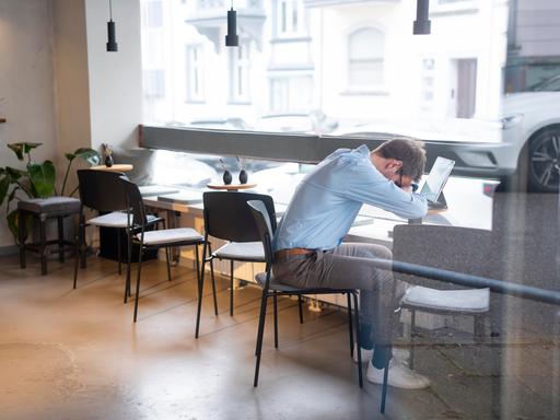Geschäftsmann, der über seinem Tablet in einem Café ein Nickerchen macht