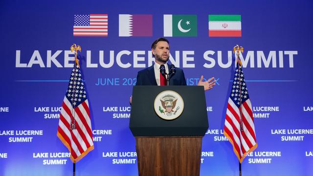 JD Vance steht an einem Redner-Pult und spricht in ein Mikrofon. Neben ihm sind 2 Flaggen von dem Land USA. Im Hintergrund sind die Flaggen von den Ländern USA, Iran, Pakistan und Katar.