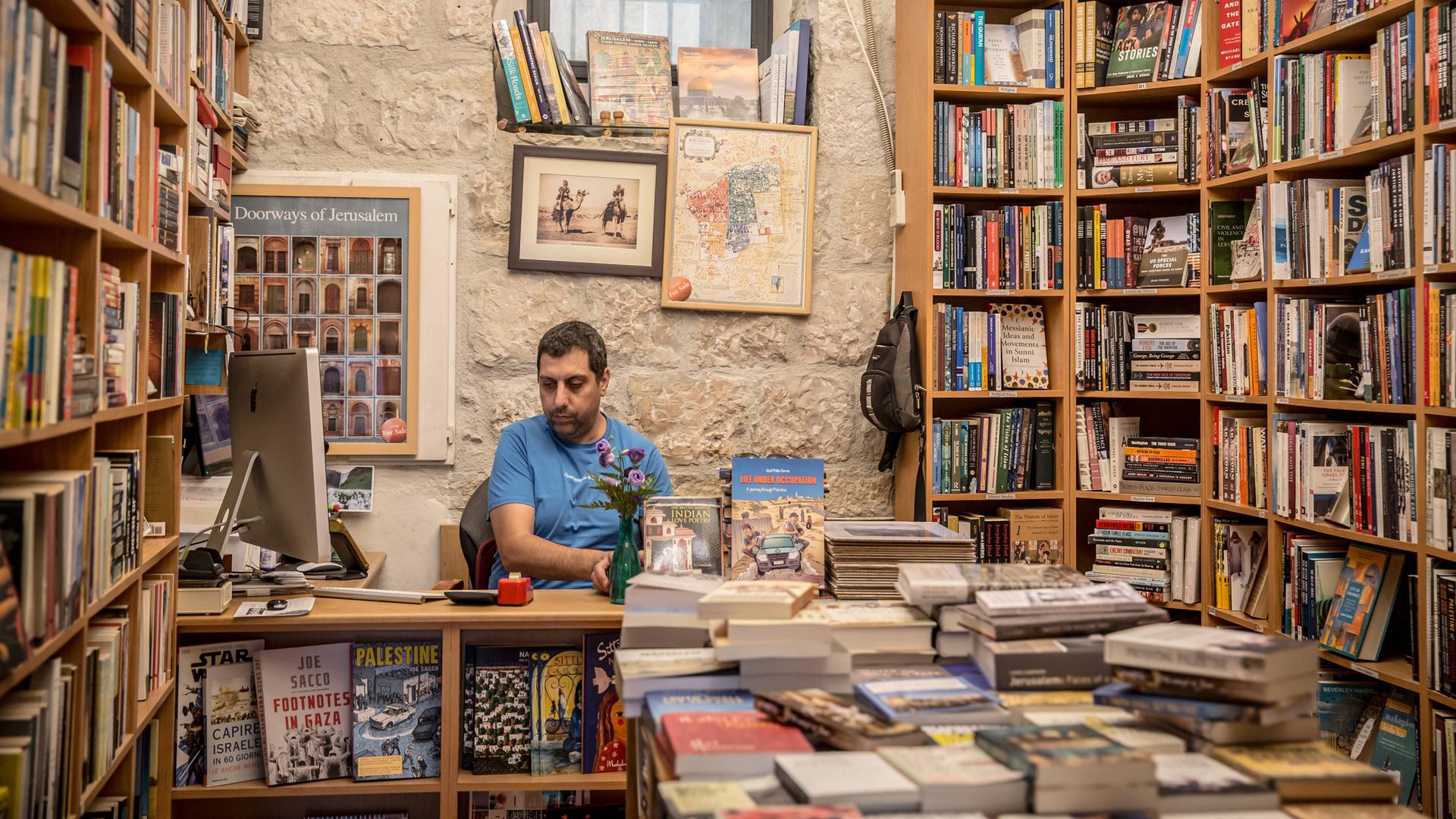 Der Besitzer des "Educational Bookshop Jerusalem" Mahmoud Muna sitzt in seiner Buchhandlung an der Kasse.