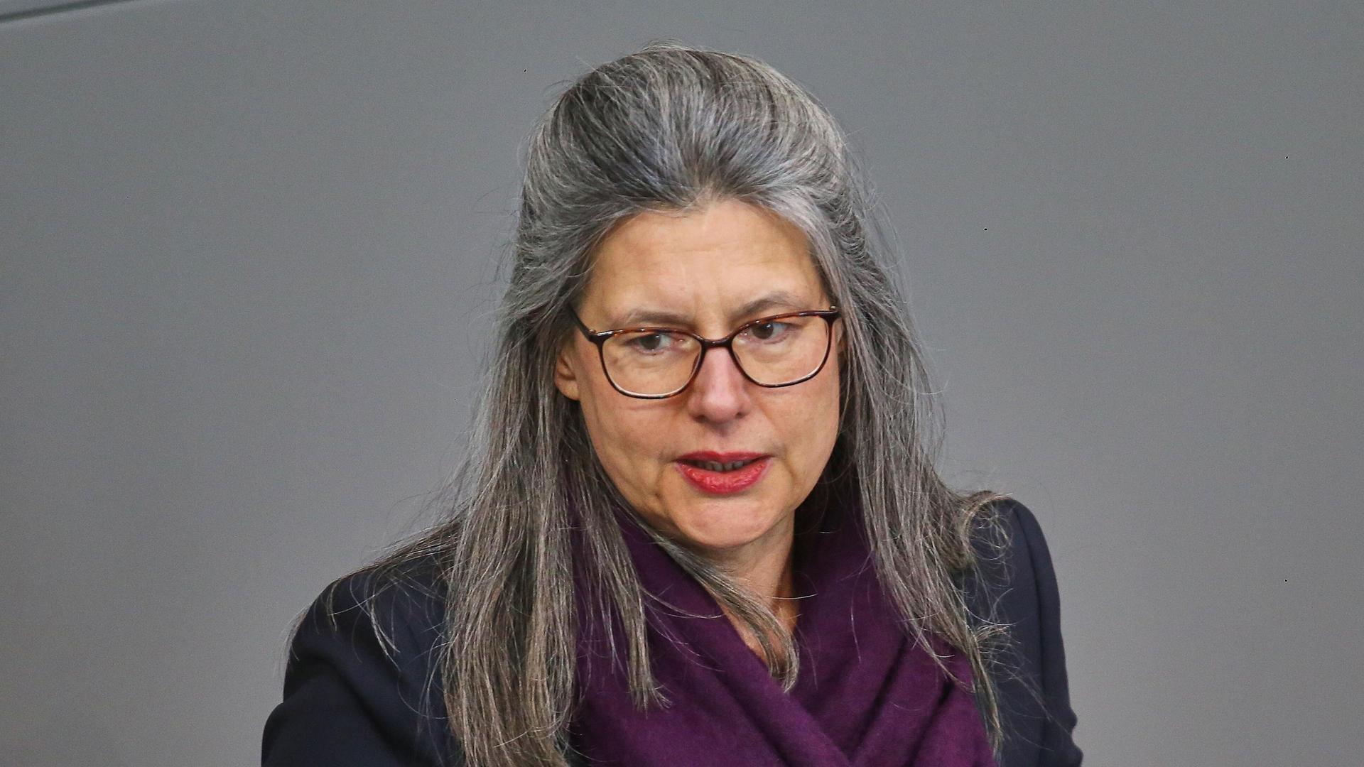 Nina Scheer am Rednerpult des Deutschen Bundestags. Die Mittfünfzigerin hat eine Brille, trägt eine dunkle Jacke und hat ein lila Tuch umgelegt.