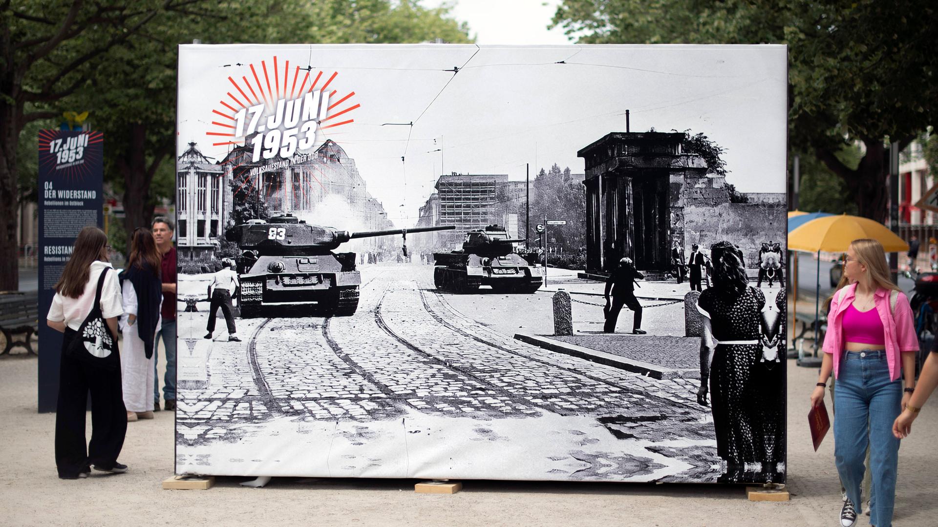 Besucher betrachten in Berlin eine der großformatigen Fotografien, die den Volksaufstand in der DDR gegen die damalige Regierung in Berlin im Jahr 1953 dokumentieren.