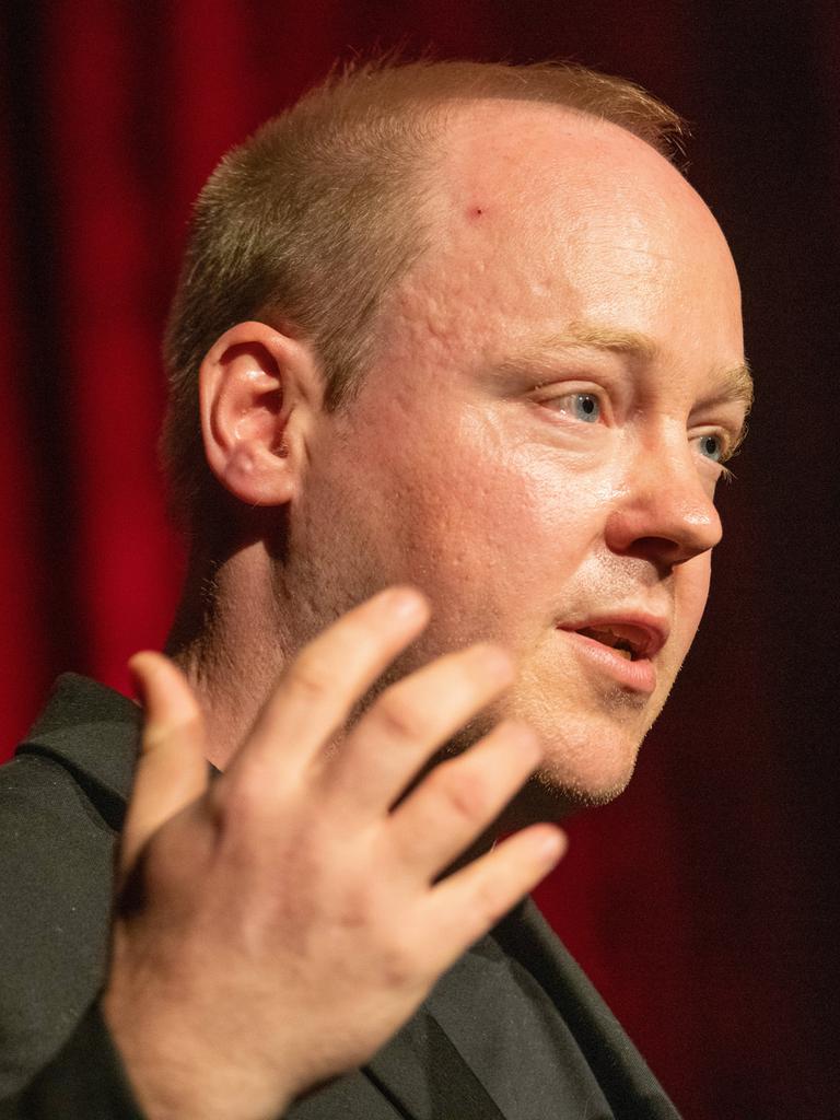 Christian Baron steht an einem Rednerpult und spricht gestikulierend in ein Mikrofon.