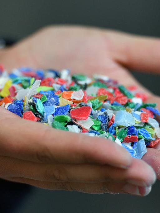 Bunte kleine Stückchen aus Kunststoffverpackungen hält eine Frau in ihren Händen