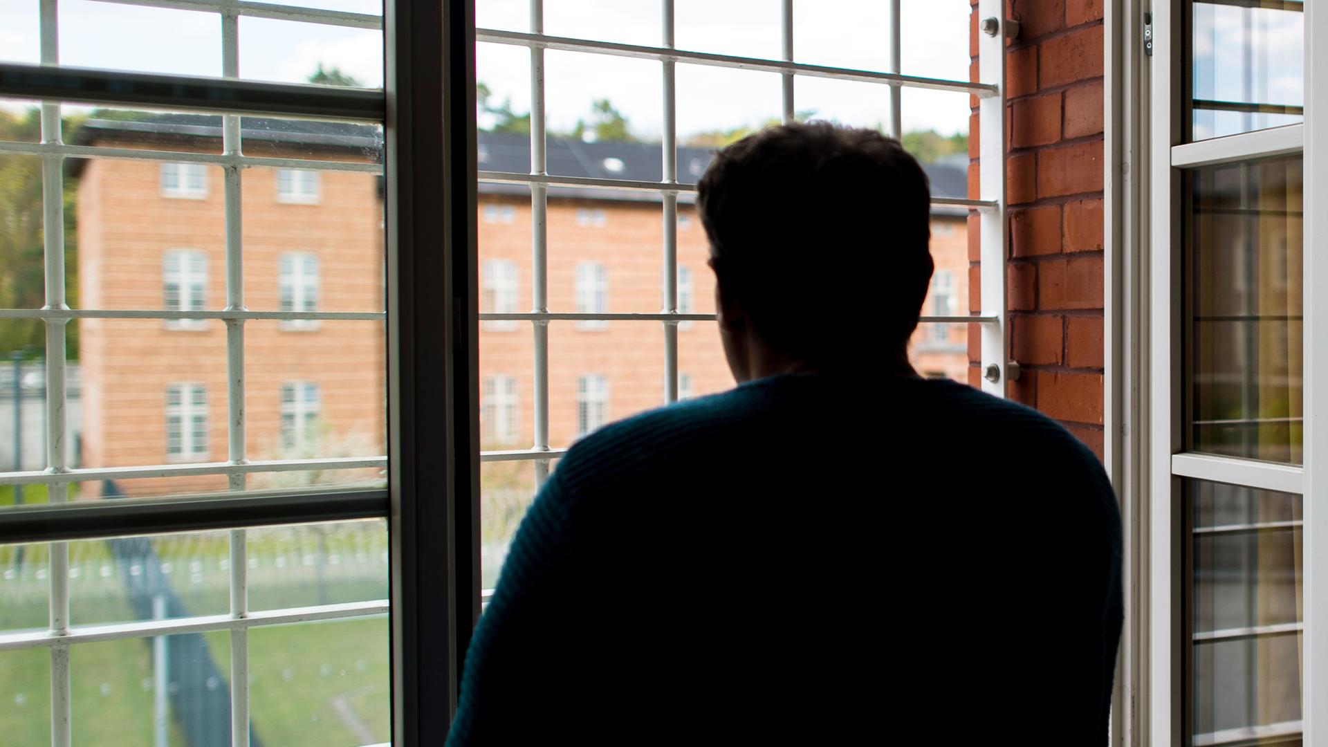 Ein Straftäter steht vor einem vergitterten Fenster in der Klinik für Forensische Psychiatrie (Maßregelvollzug) auf dem Gelände des Martin Gropius Krankenhauses in Eberswalde (Brandenburg)
