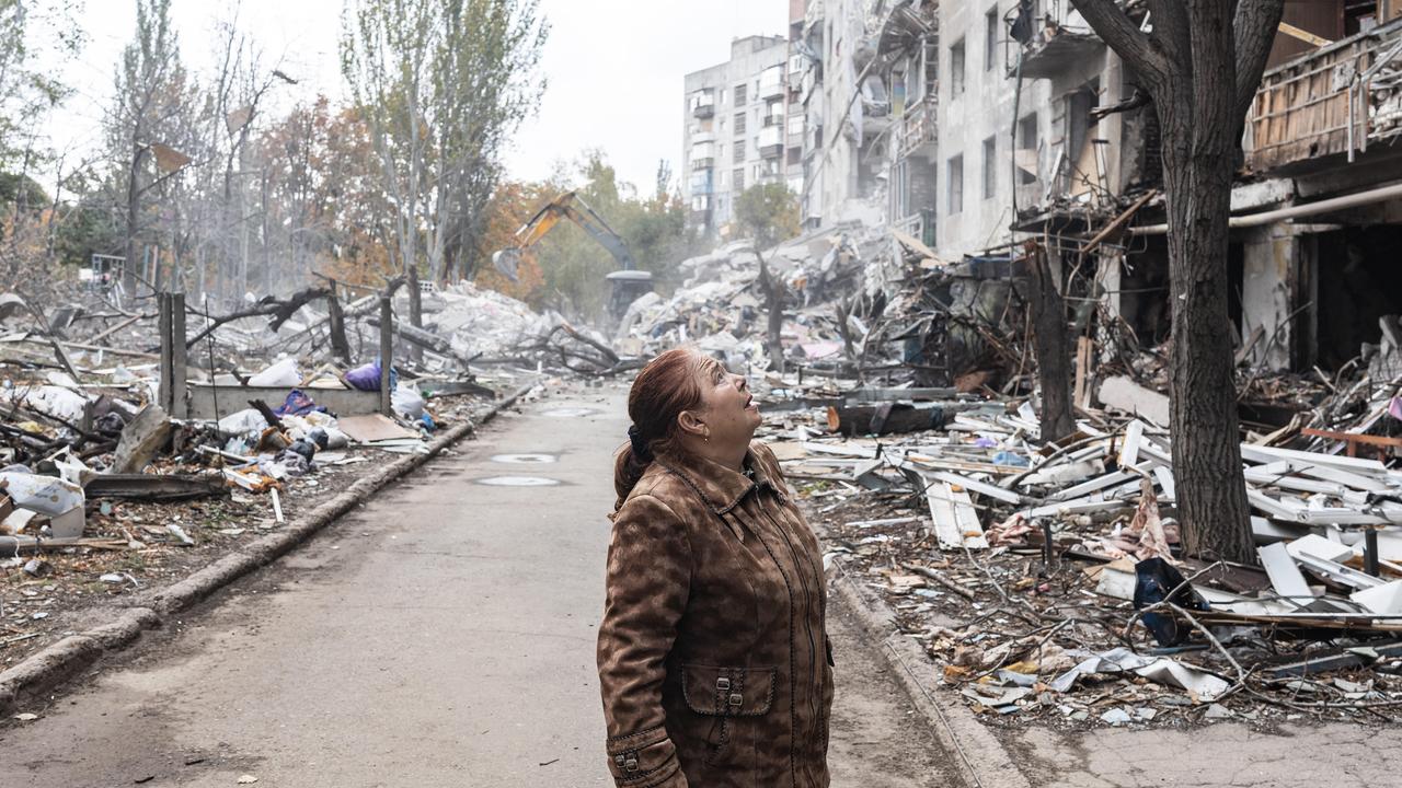 Eine Frau steht in der ukrainischen Stadt Kramatorsk inmitten zerstörter Häuser und blickt nach oben. 