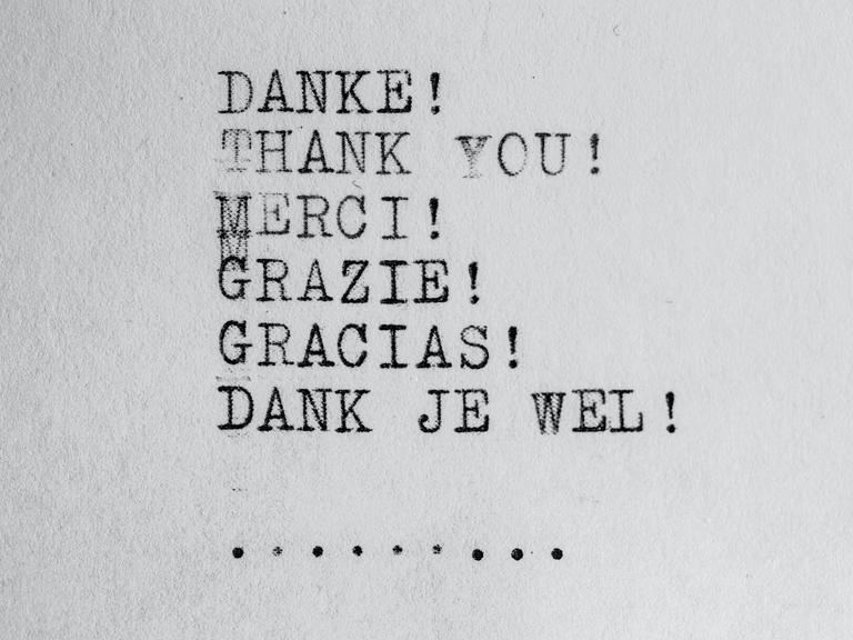 Wir sehen ein Blatt Papier auf dem das Wort "Danke" in verschiendenen Sprachen mit einer Schreibmaschine geschrieben steht. 